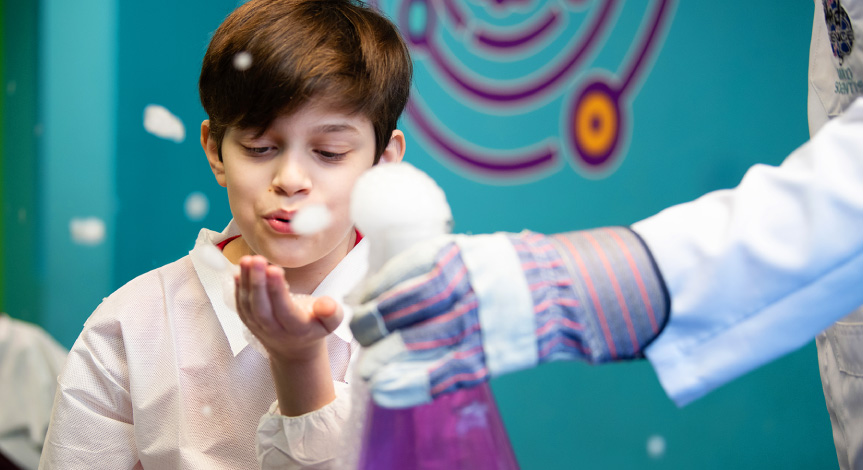 Boy blowing soap bubbles at a birthday party, after a dry ice experiment.