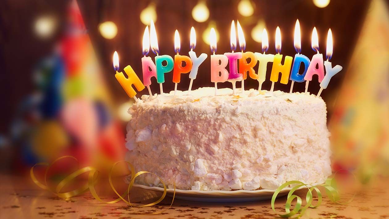 A birthday cake with lit candles that say happy birthday
